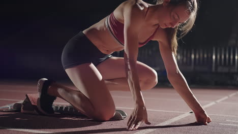 Mujer-Con-La-Mano-En-La-Pista-Mientras-Se-Agacha-En-La-Posición-Inicial-Al-Comienzo-De-Una-Carrera.-La-Atleta-Femenina-Se-Prepara-Y-Comienza.-Manos-Del-Corredor-Esperando-Al-Inicio-Frente-A-La-Línea-De-Inicio-En-El-Suelo.